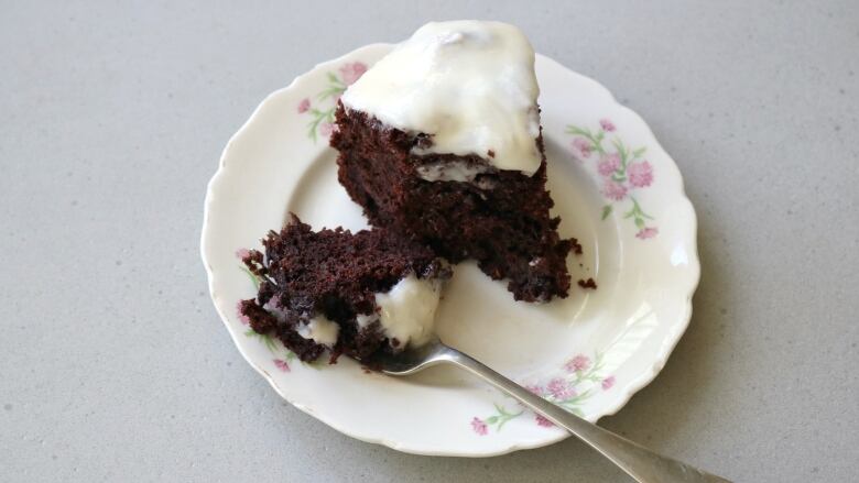 Chocolate cake with frosting on a white plate.