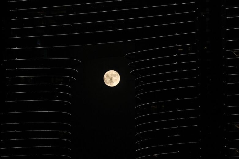 Full moon rises behind a hotel building in Dubai.