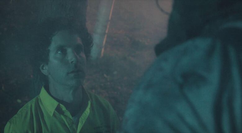 A still from a film shows a man looking up in fear at a much larger person.