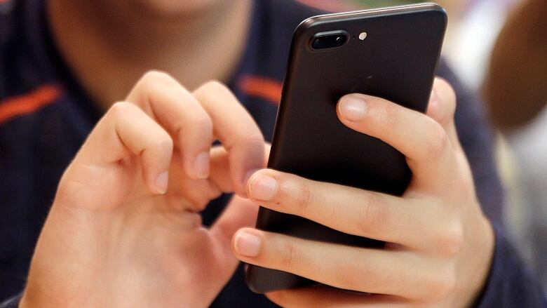 A young person holding a smartphone.