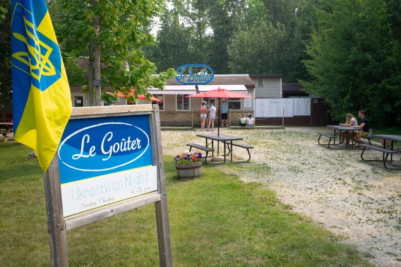 A sign that says Le Goter stands in front of a restaurant.