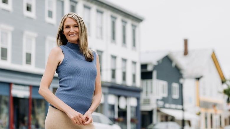 Woman wearing blue sleeveless top smiles.