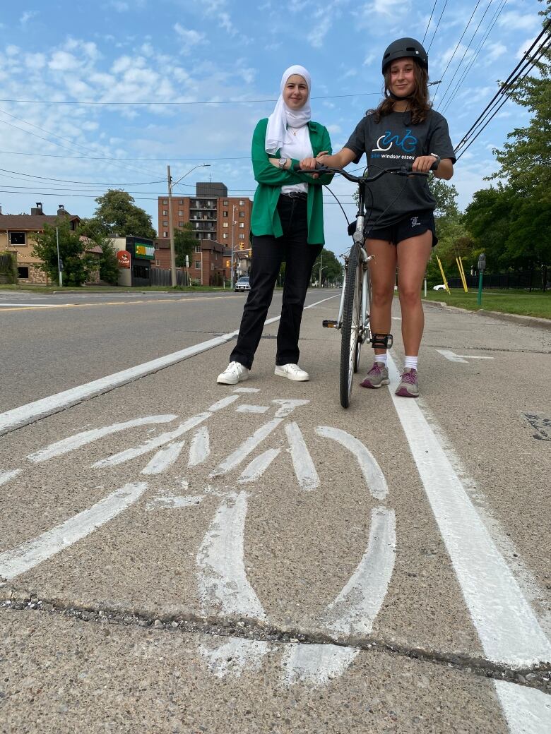 The two women stand in a bike lane on University Avenue West