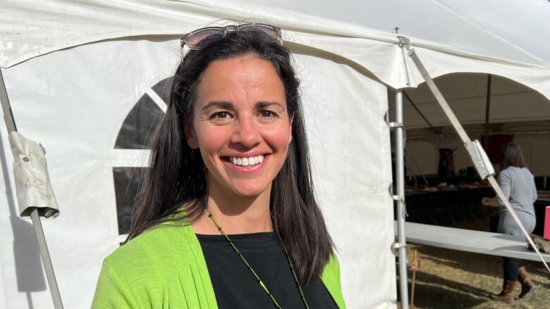 A smiling woman stands outside a big event tent.