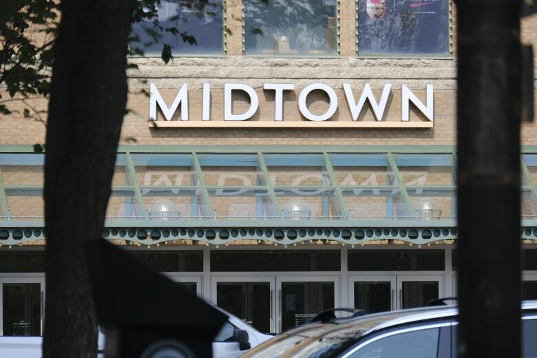 Tree branches frame the entrance to a building that features the midtown mall logo. 