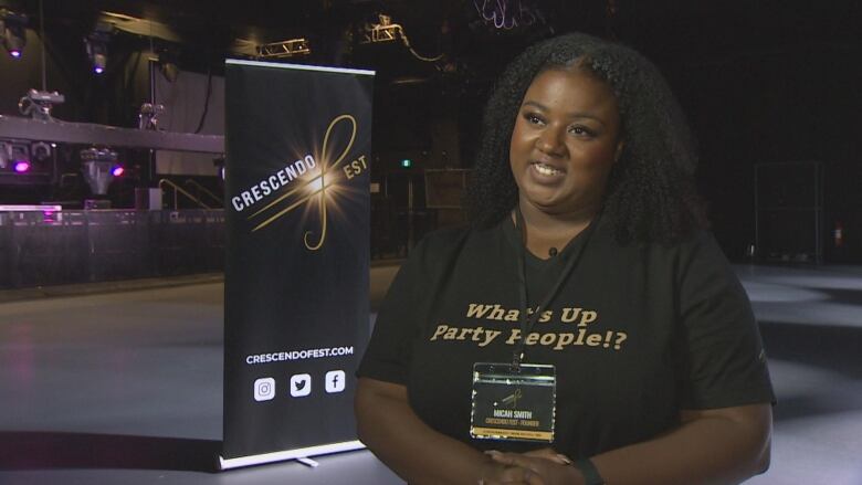 A young Black woman smiles in a dark music venue.