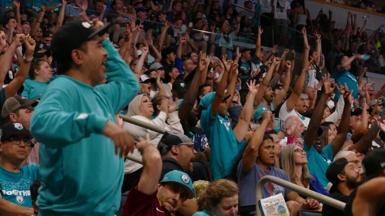 A cheering crowd sit in a arena.