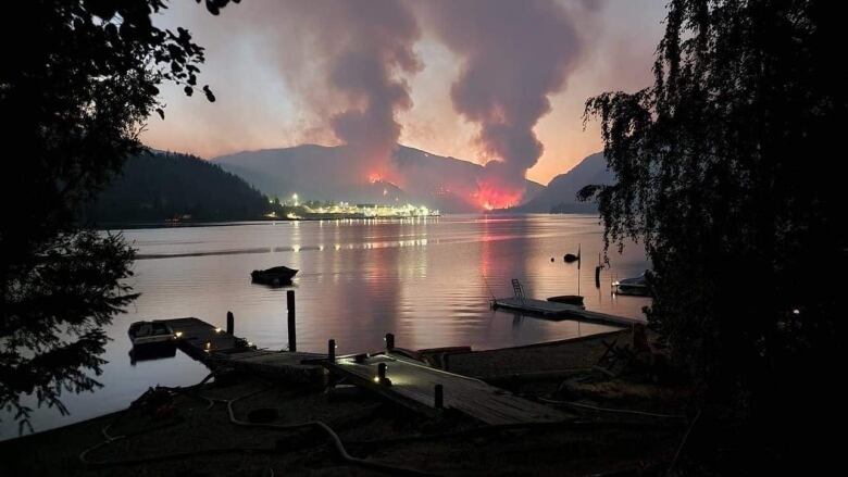 A wildfire burns across a lake.