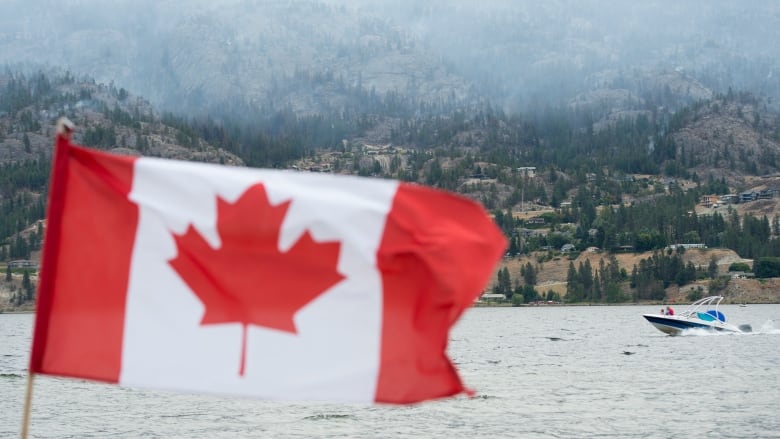 A Canada flag is pictured as a jet ski flies along a lake, with smoke visible in the background.