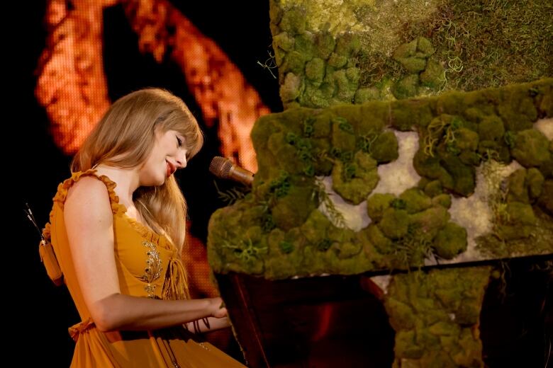 Taylor Swift playing the piano on stage.