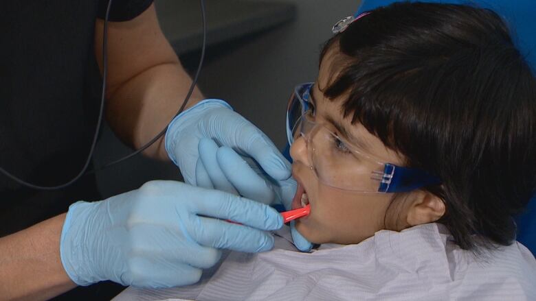 Archisha Maji, 3, is pictured with a dental hygienist who is brushing her teeth.