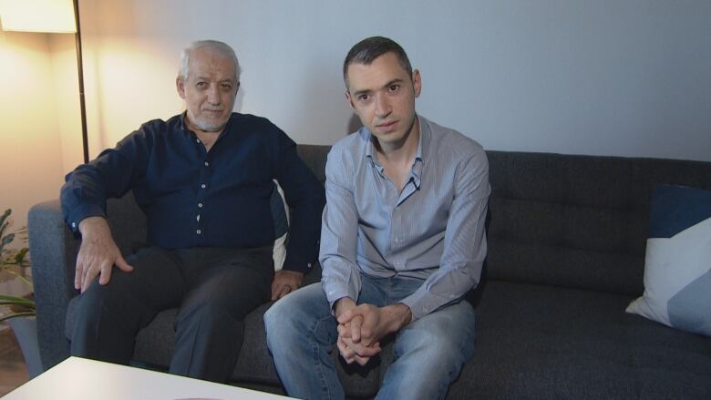 An elderly man sits next to his younger son.