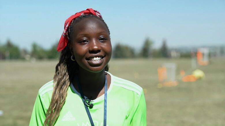 A woman is seen sporting a red bandana and wearing a green football jersey.