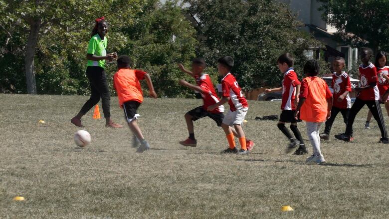 Kids in colorful jerseys are seen playing soccer on a field.