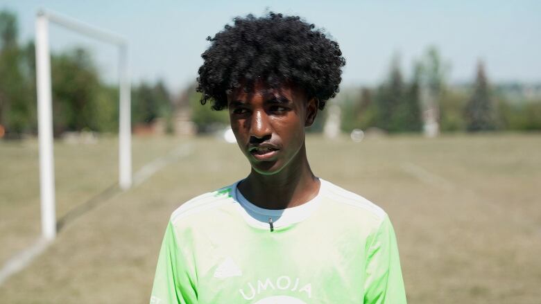 A man with curly hair is seen wearing a light green T-shirt.