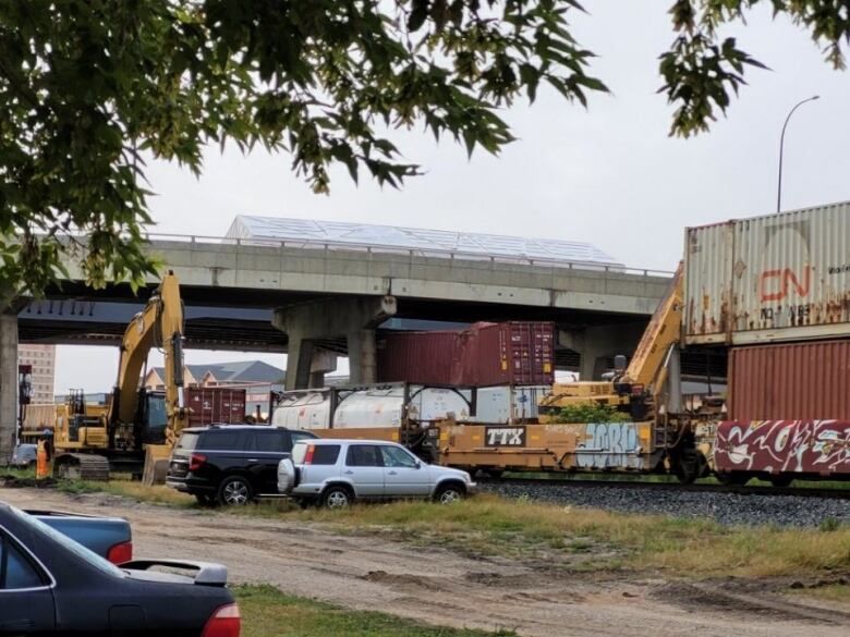 A wide shot of a damaged train car under an overpass. 