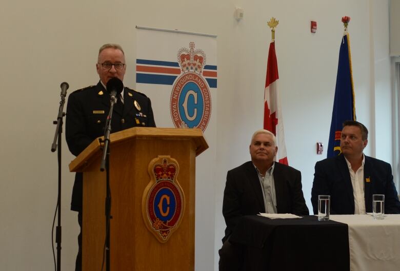 Police chief Pat Roche stands at a podium speaking into two microphones.