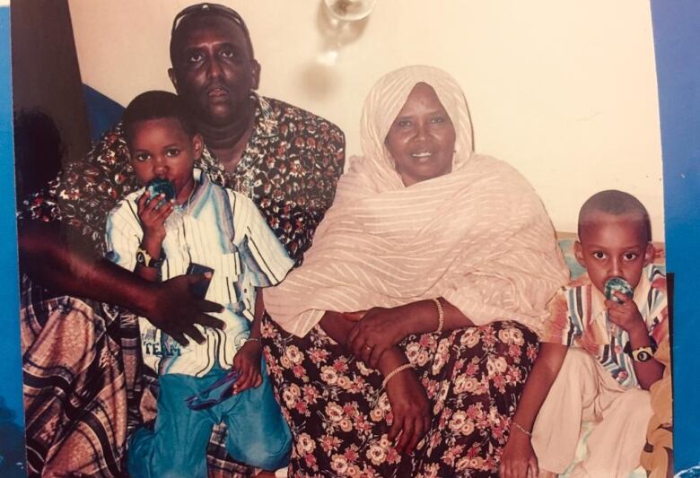 A man and  a woman sit on the floor with two young boys beside her and in his lap.