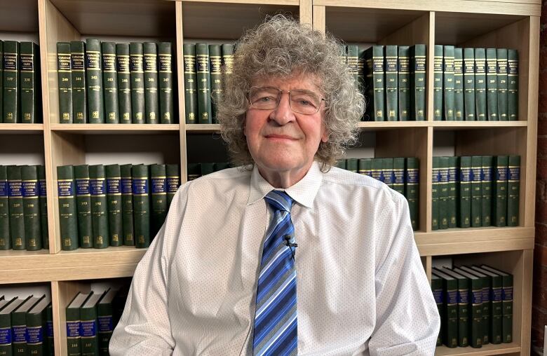 James Lockyer is sitting in his office with bookshelves in the background. 