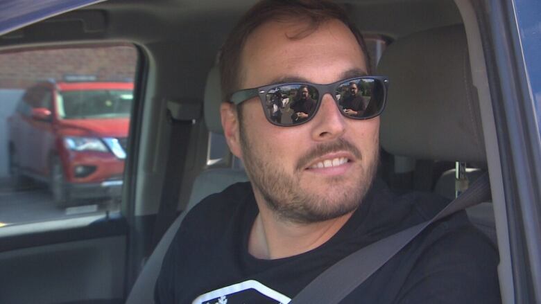 A man in sunglasses looks out of a car window