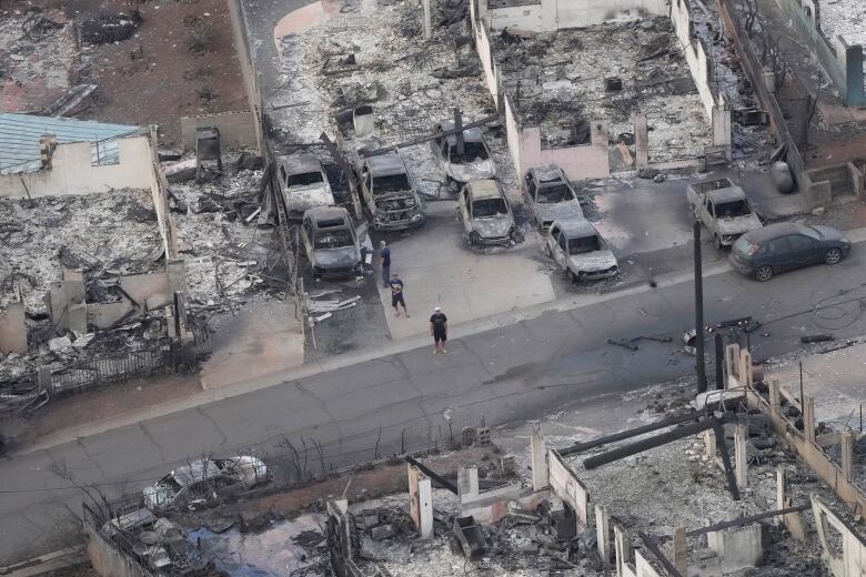 A man stands on a street destroyed by a wildfire.