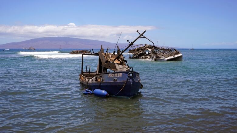 Two burnt boats float on water.