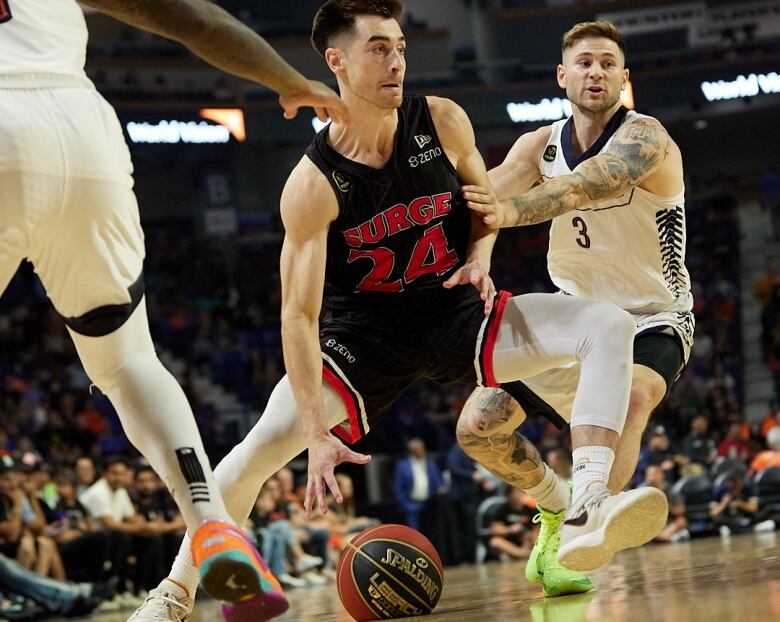 Two men running, one is dribbling a basketball. 