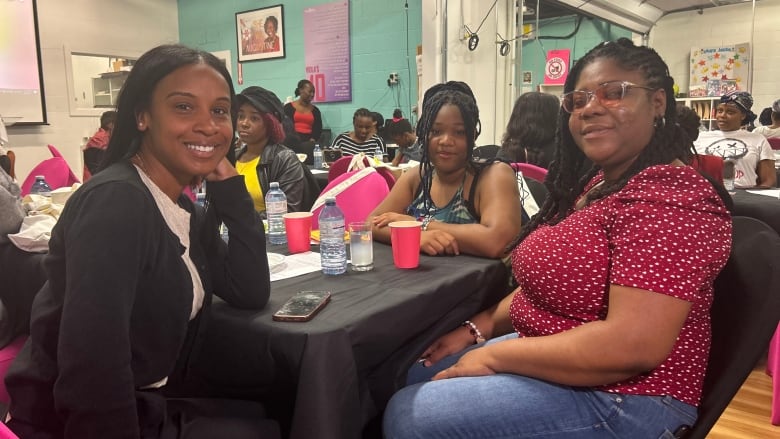 Three women at an event smile for a photo.