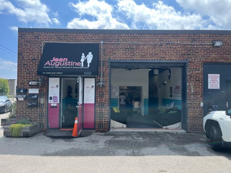 A picture of a building, with the garage opened showing couches and a glimpse of the inside of the building. 