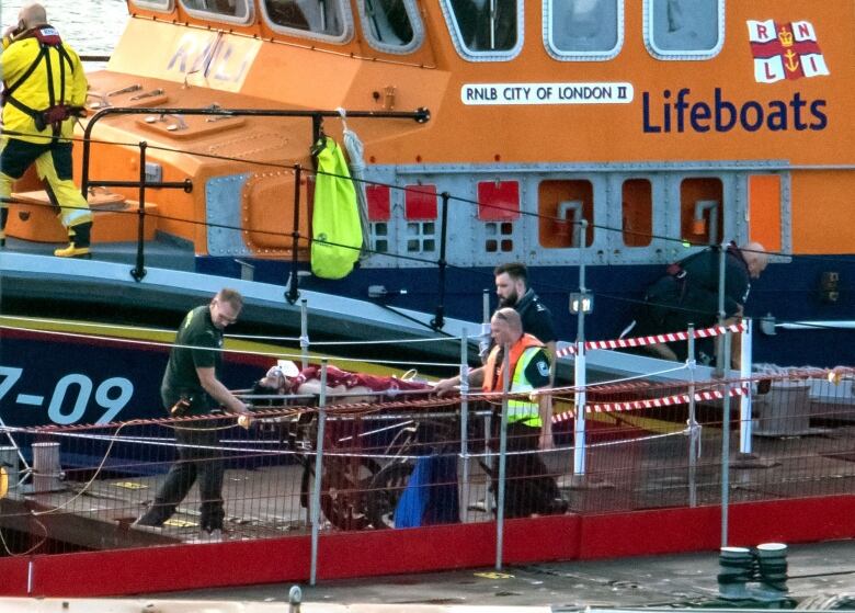 Paramedics assist a person on a stretcher.