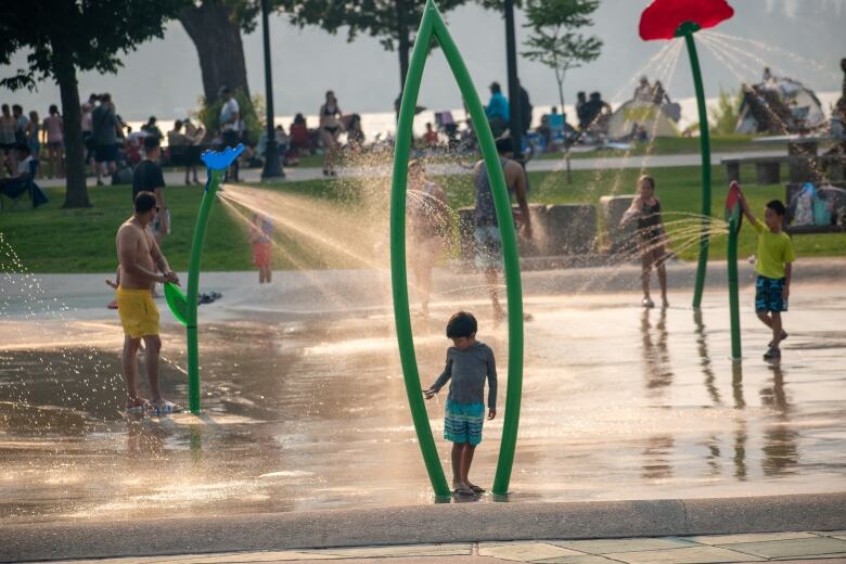 Children and parents frolic at an outdoor spray park.