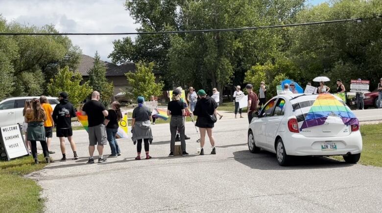 Two groups of protesters are pictured on opposite ends of a street, carrying signs and flags.