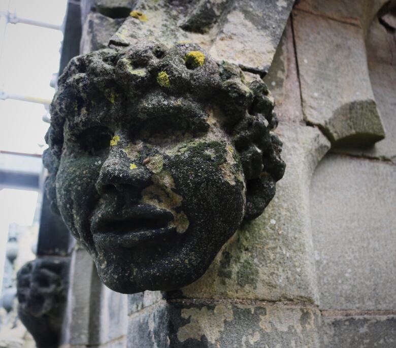 A carved stone head covered in lichen