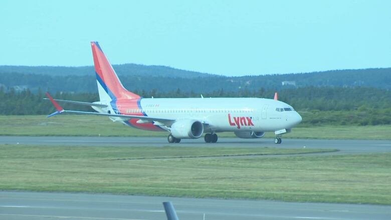 A white plane with Lynx in red lettering touches down on an airstrip. 