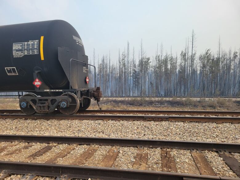 a railcar with a burned forest behind