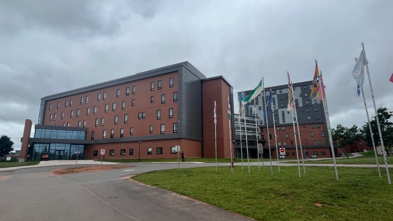 Flagpoles are visible against the backdrop of the new UPEI residence.