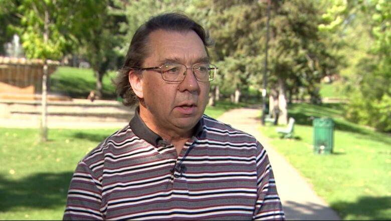 A bespectacled man in a strip polo shirt.