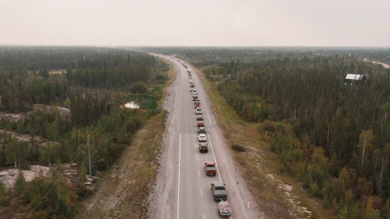 Vehicles form a single line stretching as far as the eye can see on a highway out of Yellowknife.