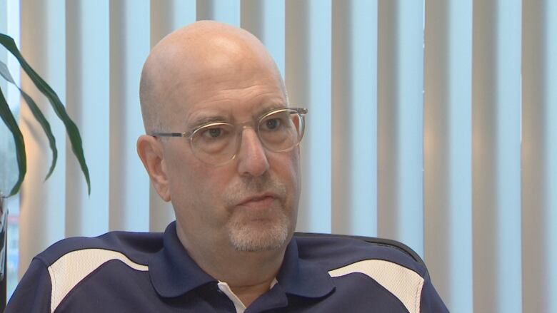 A man in a blue polo shirt speaks to the camera.