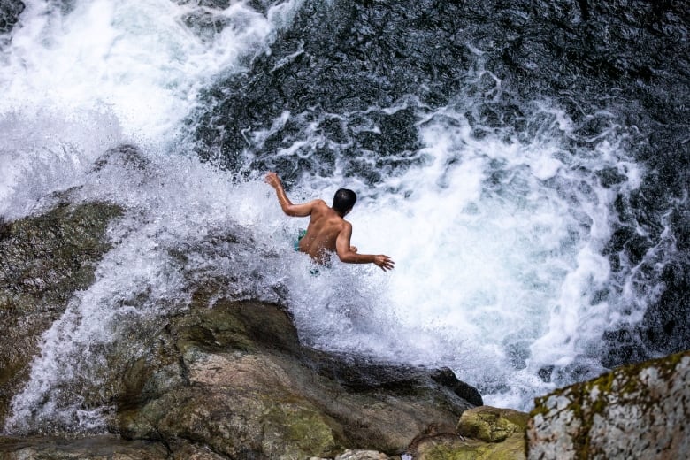 A cliff jumper plunges into the water at Lynn Canyon.