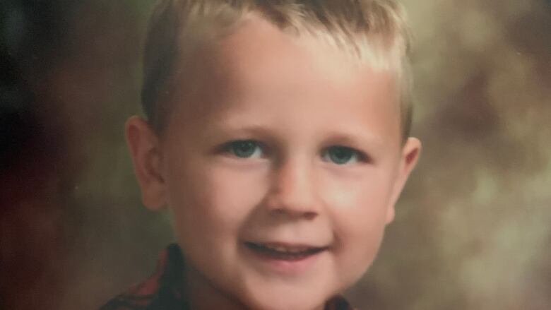 A young boy smiles for a school photo.