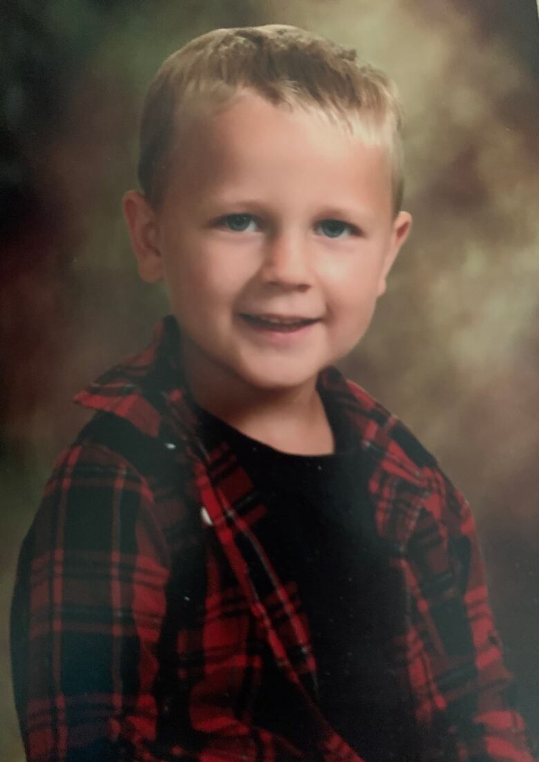 A young boy smiles for a school photo.