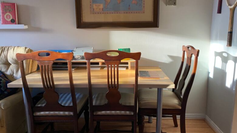 A wooden dining table with three chairs