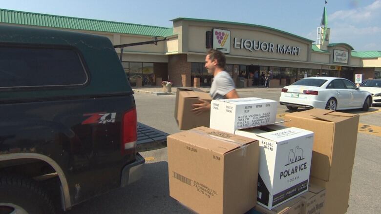 A man loads boxes into the back of a black pickup truck.