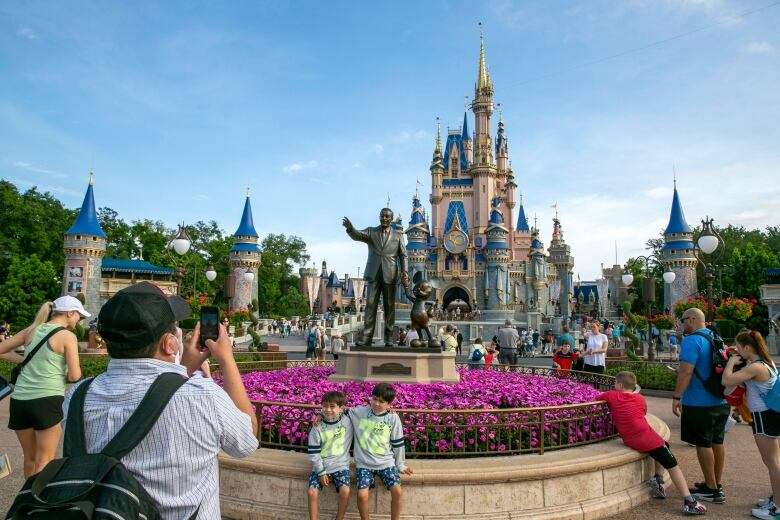 People take photos in a  crowd of  a castle in a theme park