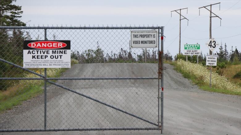 A chain link gate is shown with a sign saying 'Danger Active Mine Keep Out.'