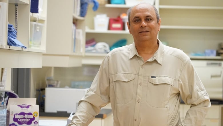 A photo of a man standing in a clinic with his hand on a table.