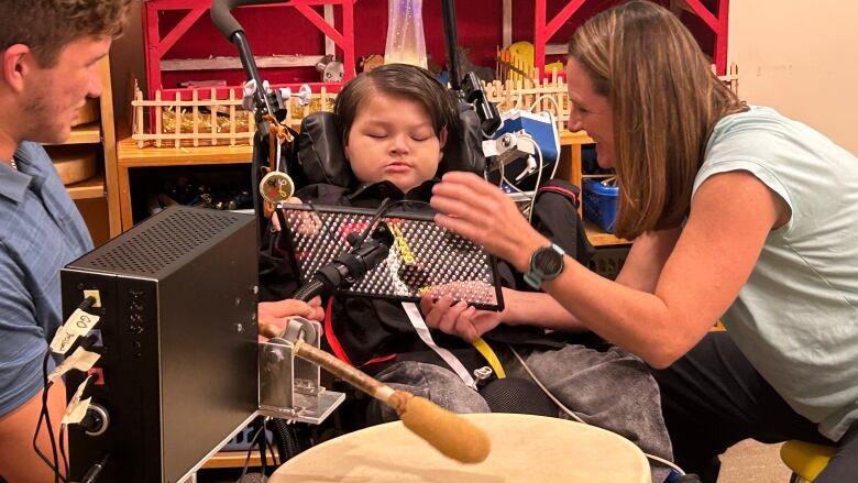 Gerry Lewis plays his custom-made drum Tuesday with the help of his occupational therapist Jennifer Neill and UPEI engineering student Christian d'Entremont.