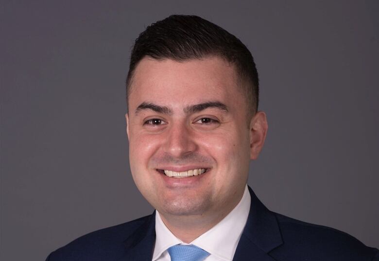 A man in a suit smiles for the camera.