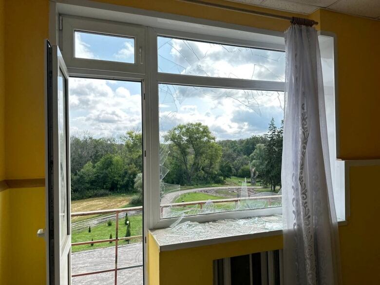 A broken window is shown from the interior of an apartment unit.